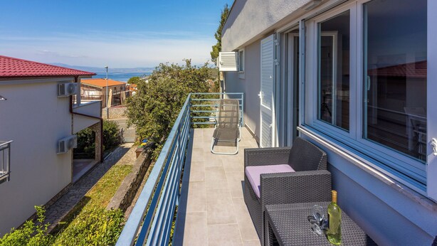 A balcony with wicker furniture, a glass door, and a view of the sea. - Apartment Vito (Njivice)