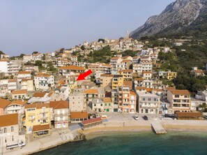 A coastal town with buildings, a beach, and a mountain in the background. - House Lea (Podgora)