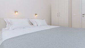 Ein Schlafzimmer mit einem großen Bett, zwei Wandleuchten und einem zweitürigen Kleiderschrank.