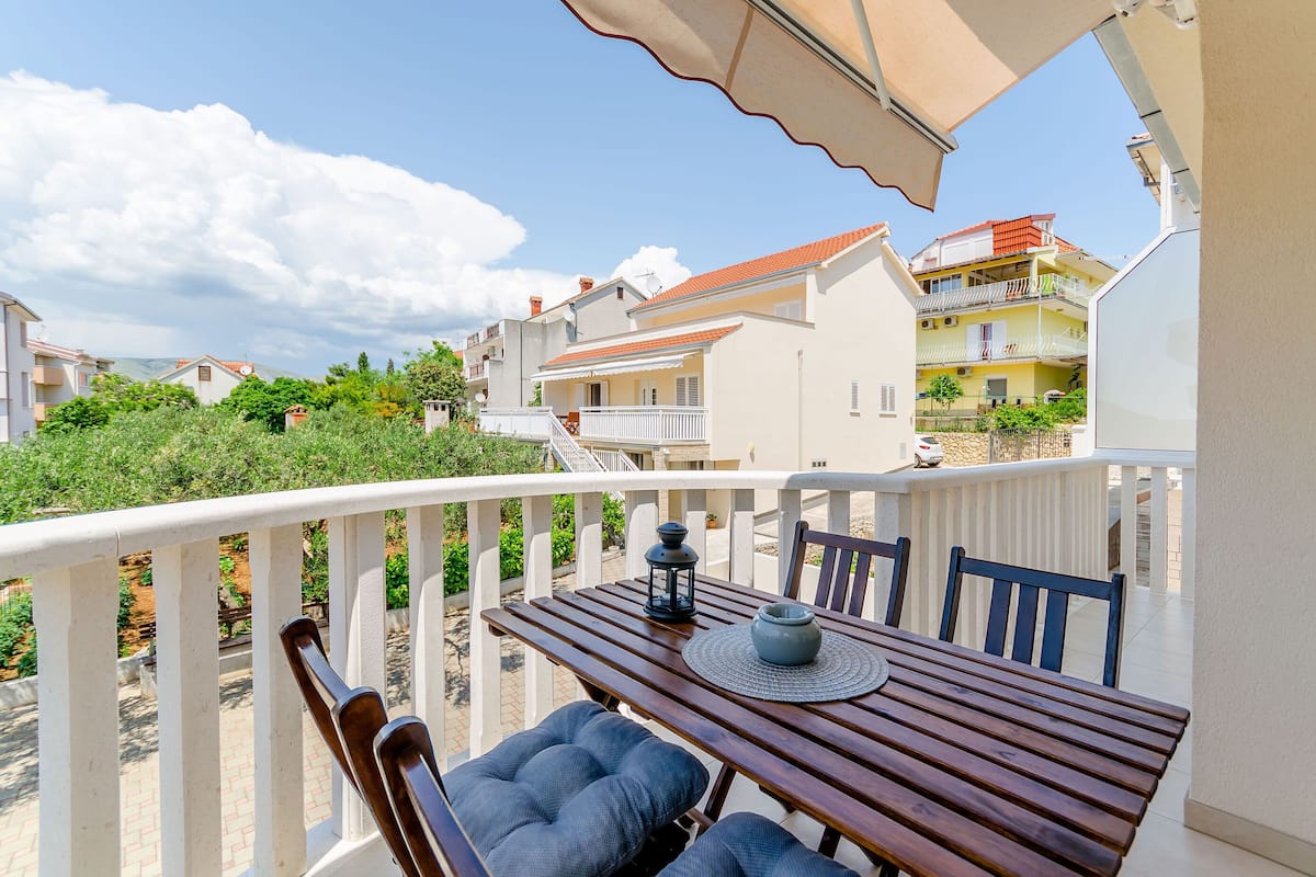 A balcony with a wooden table, two chairs, and a lantern.