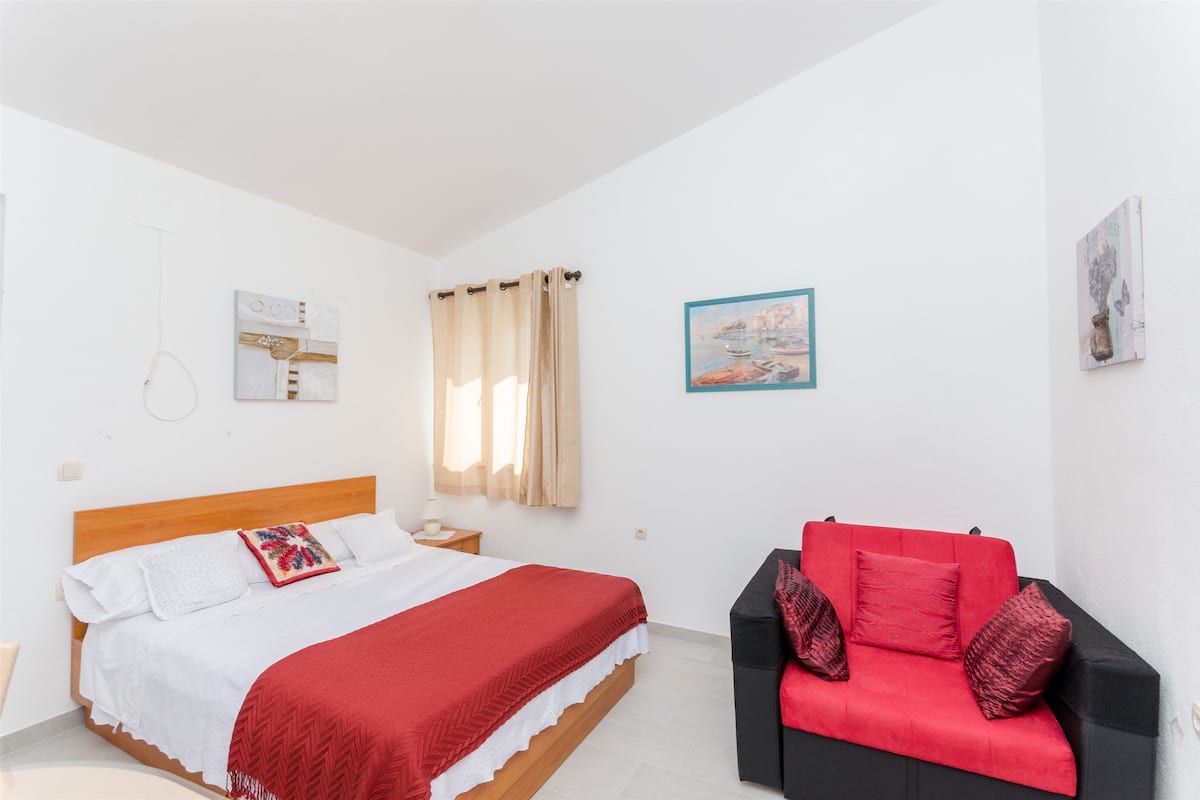 Un dormitorio con una cama, un sofá rojo y un cuadro en la pared.