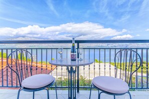 A balcony with two chairs and a table, overlooking a mountainous landscape and a body of water. - Apartments Rose (Sucuraj)