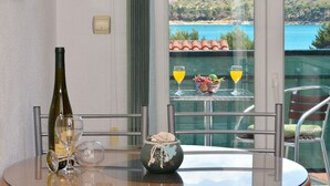 A table with a wine bottle, two wine glasses, a bowl of fruit, and two glasses of orange juice. - Apartments Marija (Trogir)