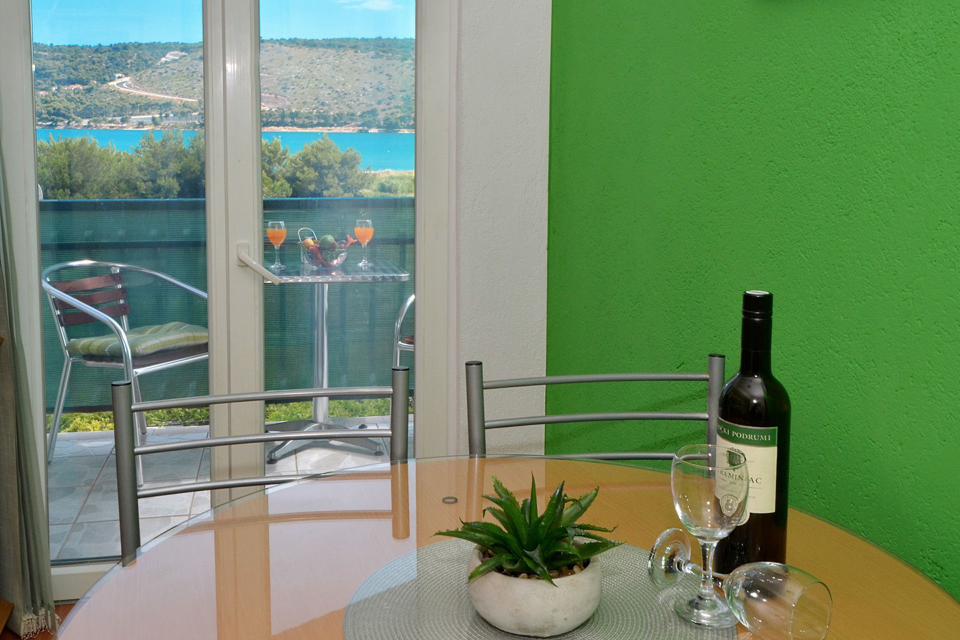 A dining table with a bottle of wine, two glasses, and a potted plant.
