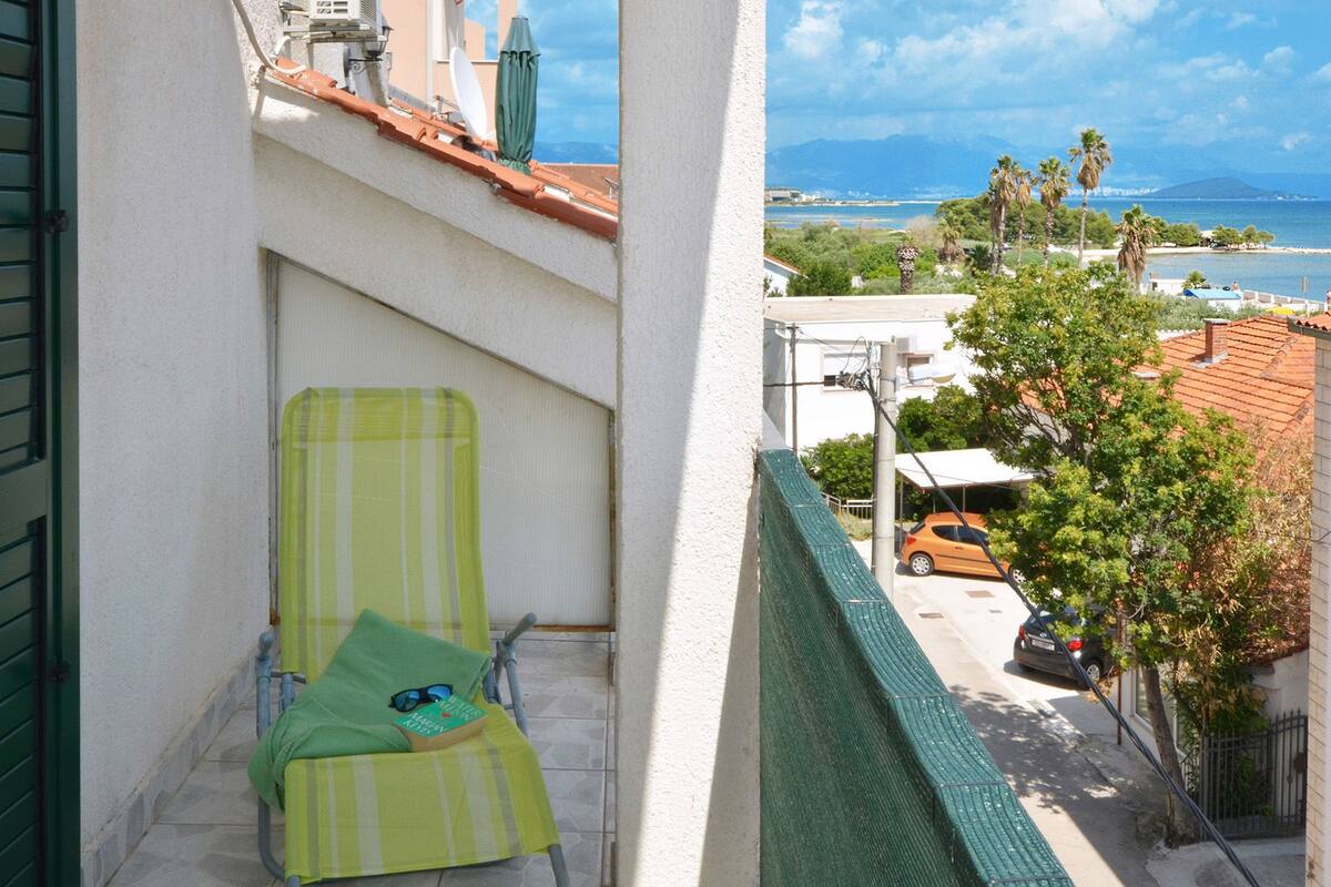 A balcony with a green chair, a book, and sunglasses.