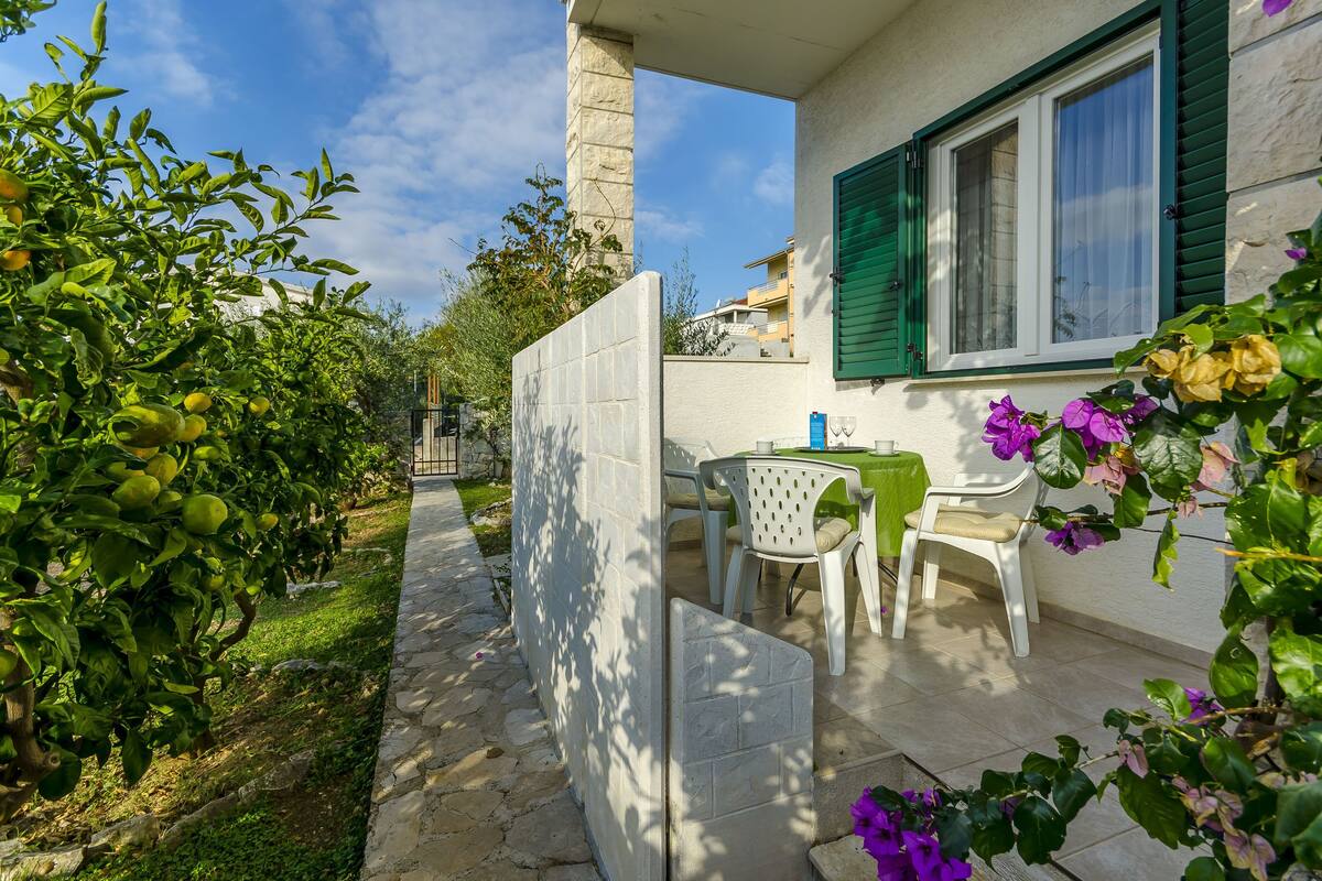 A patio with a table and chairs, a stone pathway, and a view of a building in the background.