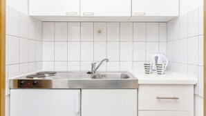 A modern kitchen with white cabinets, a stainless steel sink, and a kettle on the countertop. - Apartments Mate (Okrug Gornji)