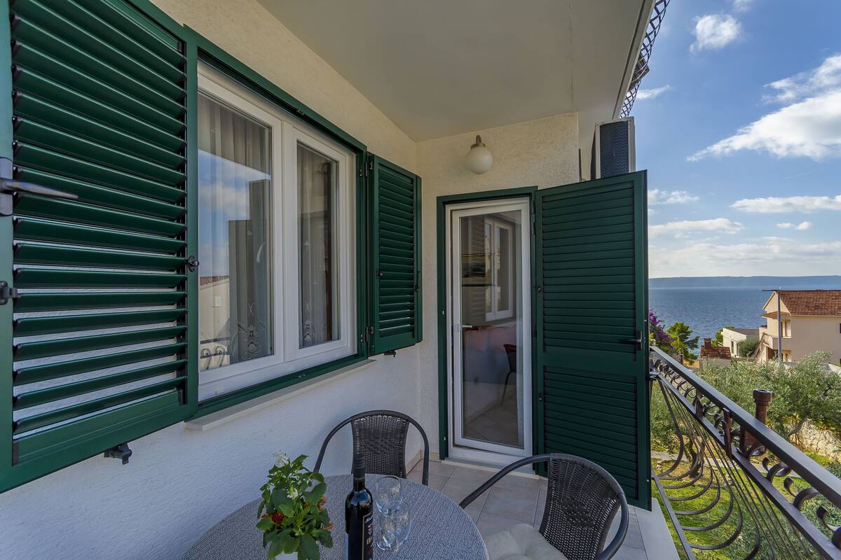 A balcony with a table, chairs, and a bottle.
