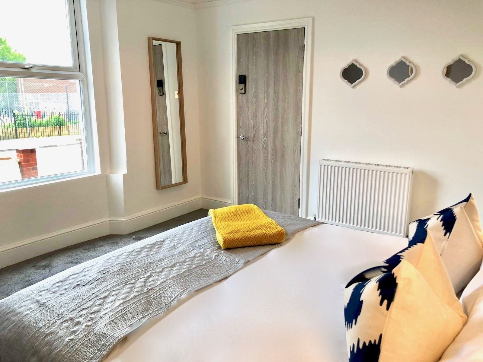 A bedroom with a bed, a window, a door, and a radiator.