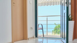 Une chambre dotée d’une porte-fenêtre coulissante donnant sur un balcon avec vue sur la mer.