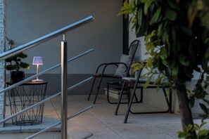 A staircase with a metal railing, a small table with a lamp, and a chair.