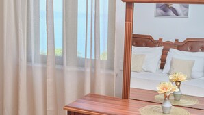 Une chambre à coucher avec une commode en bois, un miroir et deux vases ornés de fleurs, placés sur la commode.