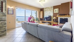A modern living room with a large grey sofa, a flat-screen TV, and a fireplace. - Apartment Paradise View (Okrug Gornji)