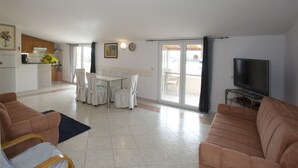 Un grand salon comprenant un canapé, un téléviseur et une table à manger avec des chaises.