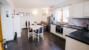 Eine moderne Küche mit weißen Schränken, einem Esstisch mit Stühlen, einem Kühlschrank und einem Herd.