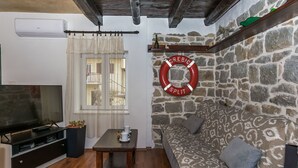 Una sala de estar con pared de piedra, un sofá, un televisor y una mesita.