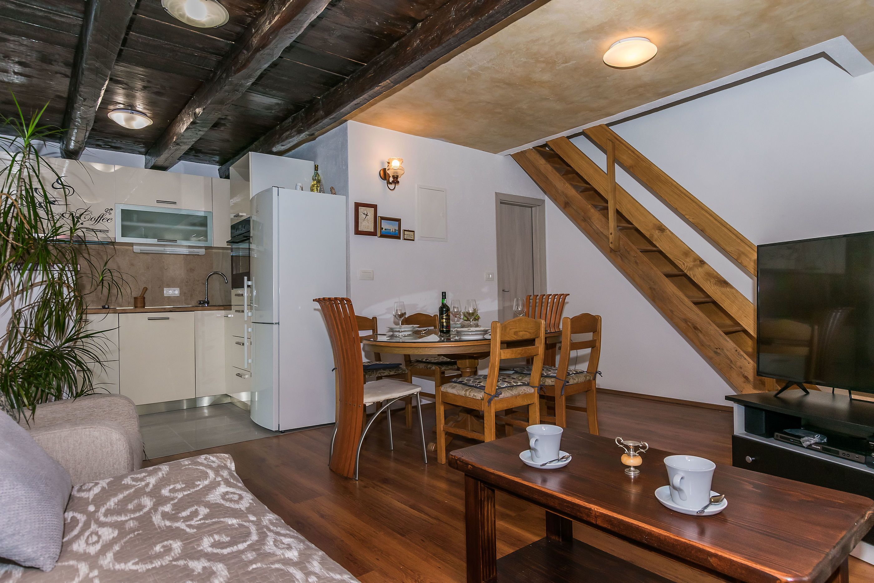 A dining area with wooden chairs, a table, and a television.