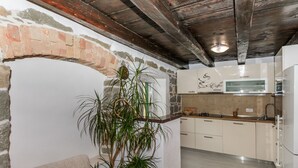 Una cocina acogedora con un arco de piedra, vigas de madera en el techo y una planta grande en maceta.