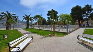 Un parque con bancos, juegos infantiles y vista a un cuerpo de agua.