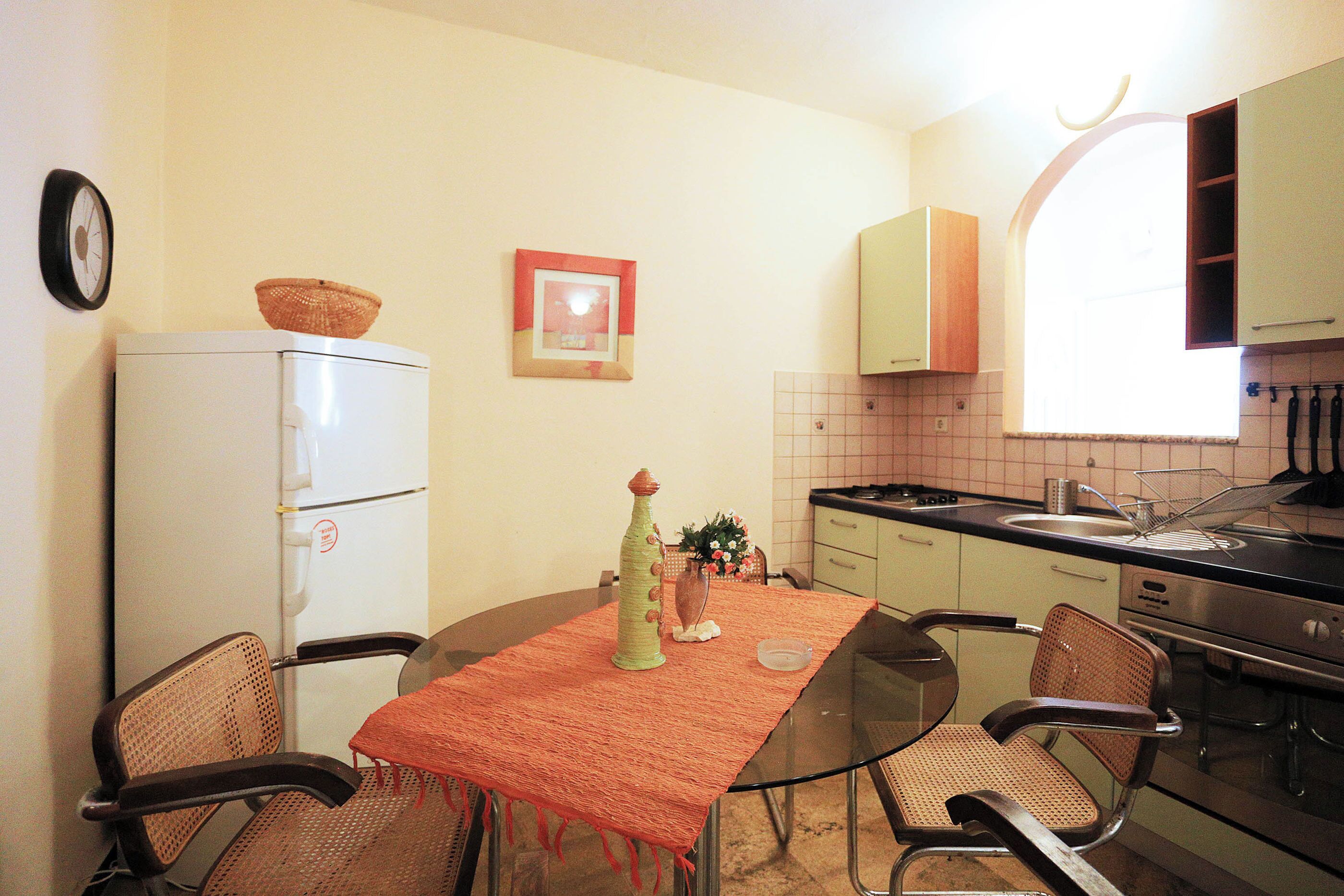 A compact kitchen with a refrigerator, a dining table with chairs, and a window providing natural light.