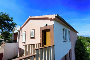 A two-story building with a balcony, a satellite dish, and a door with a window.