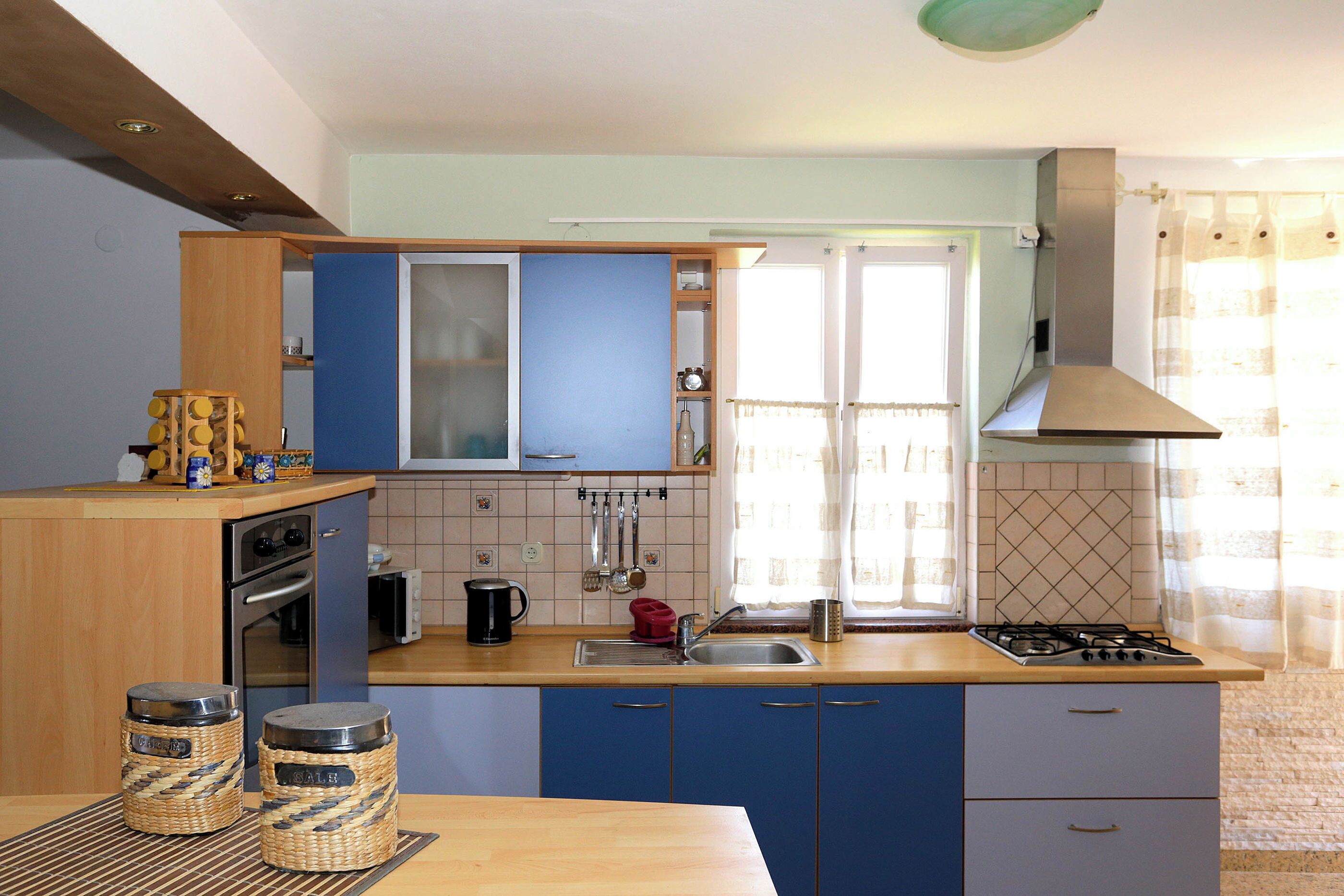Une cuisine avec des armoires bleues, une cuisinière à gaz, un évier et un four à micro-ondes.