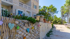 A building with a stone facade, a balcony, and a gravel driveway. - Apartments Vila Jelka (Vrboska)