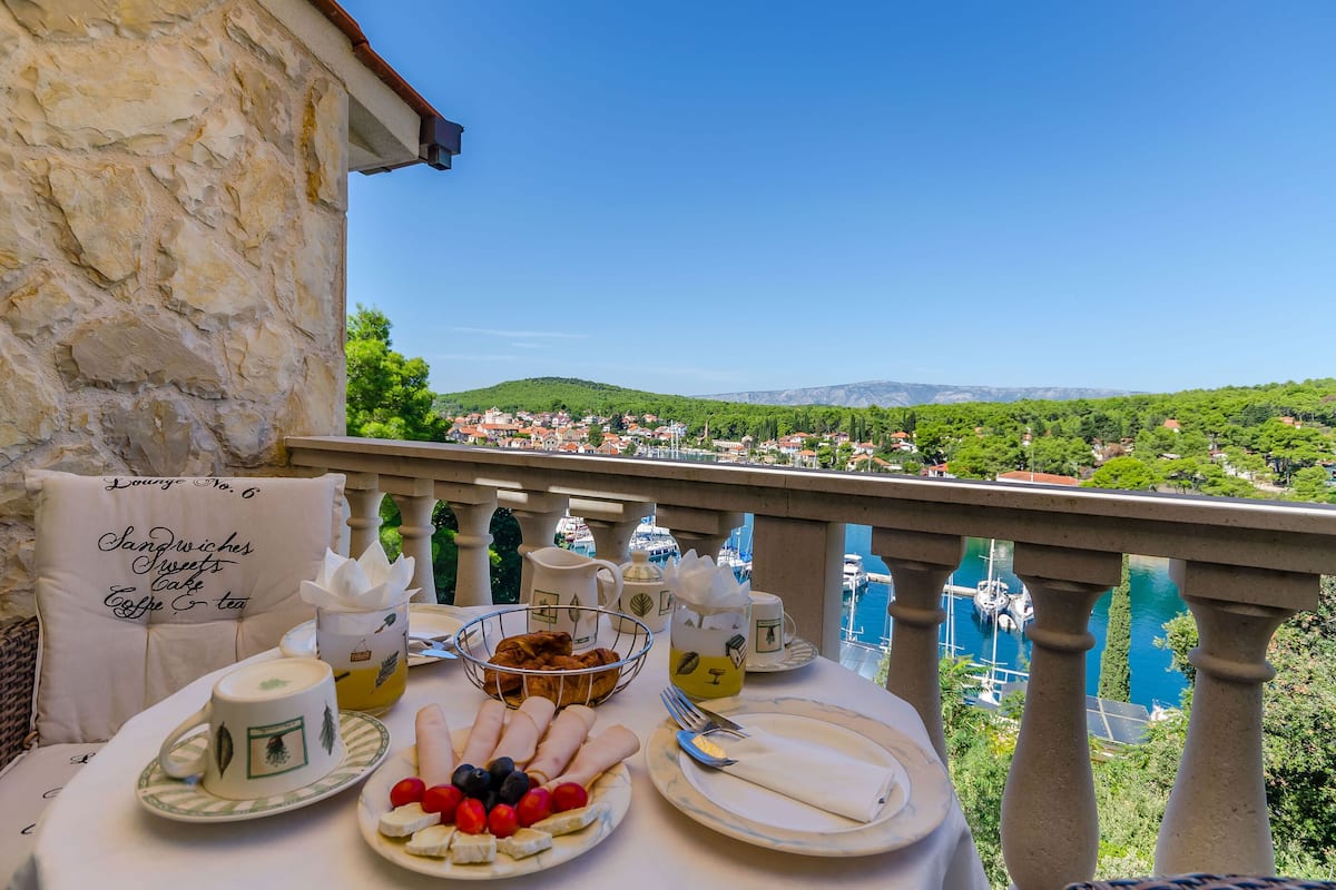 A table set for breakfast with a scenic view of a town and mountains.