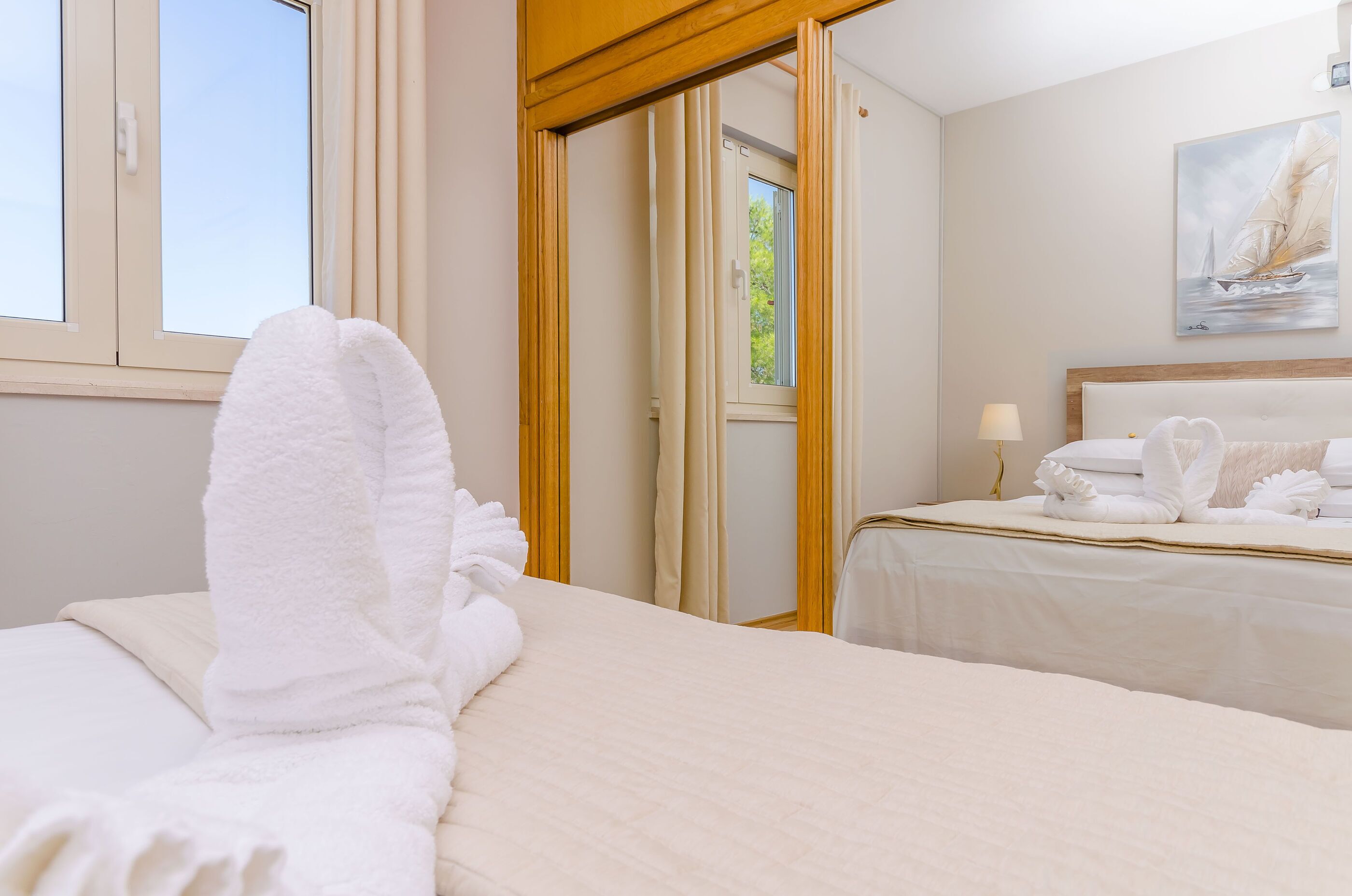 Une chambre d’hôtel avec deux lits, une fenêtre, un tableau et une porte donnant sur un balcon.