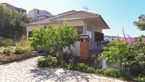 A two-story house with a tiled roof, a brick chimney, and a balcony with a metal railing. - Apartment Katica (Trogir)