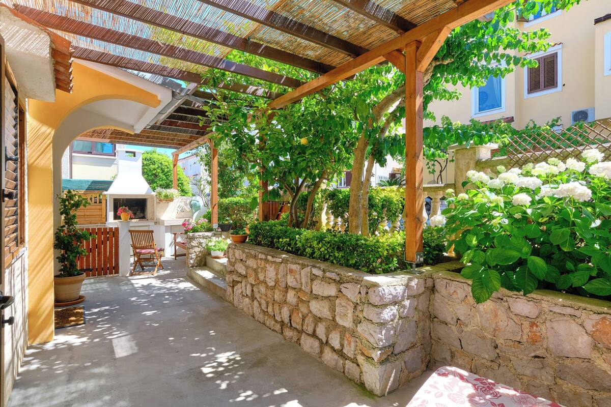 Un espace extérieur abrité, doté de murs en pierre, de mobilier en bois et de plantes en pot.