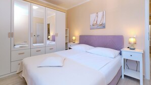 Un dormitorio con cama, mesitas de noche, armario y un cuadro en la pared.