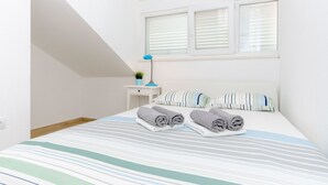 Una camera da letto con un letto, cuscini, un comodino, una lampada e una finestra.