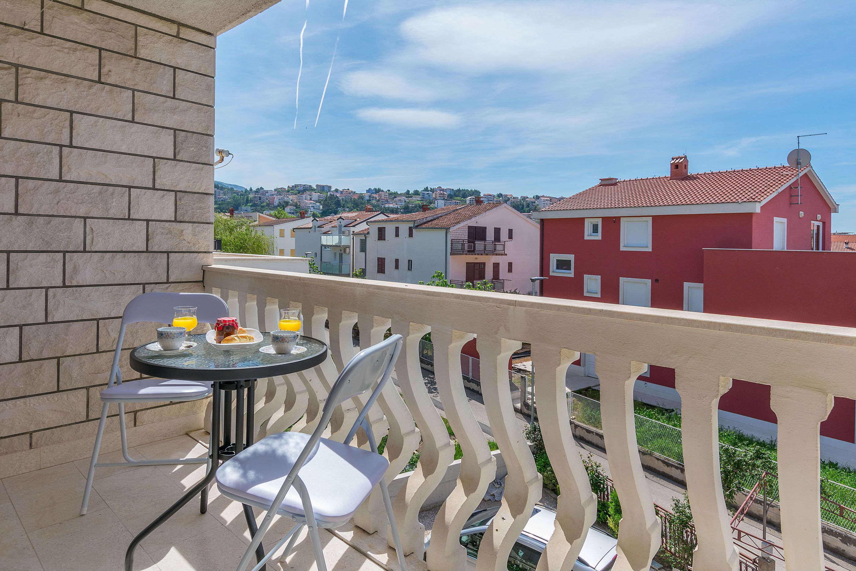 A balcony with a table, chairs, and a view of the town.
