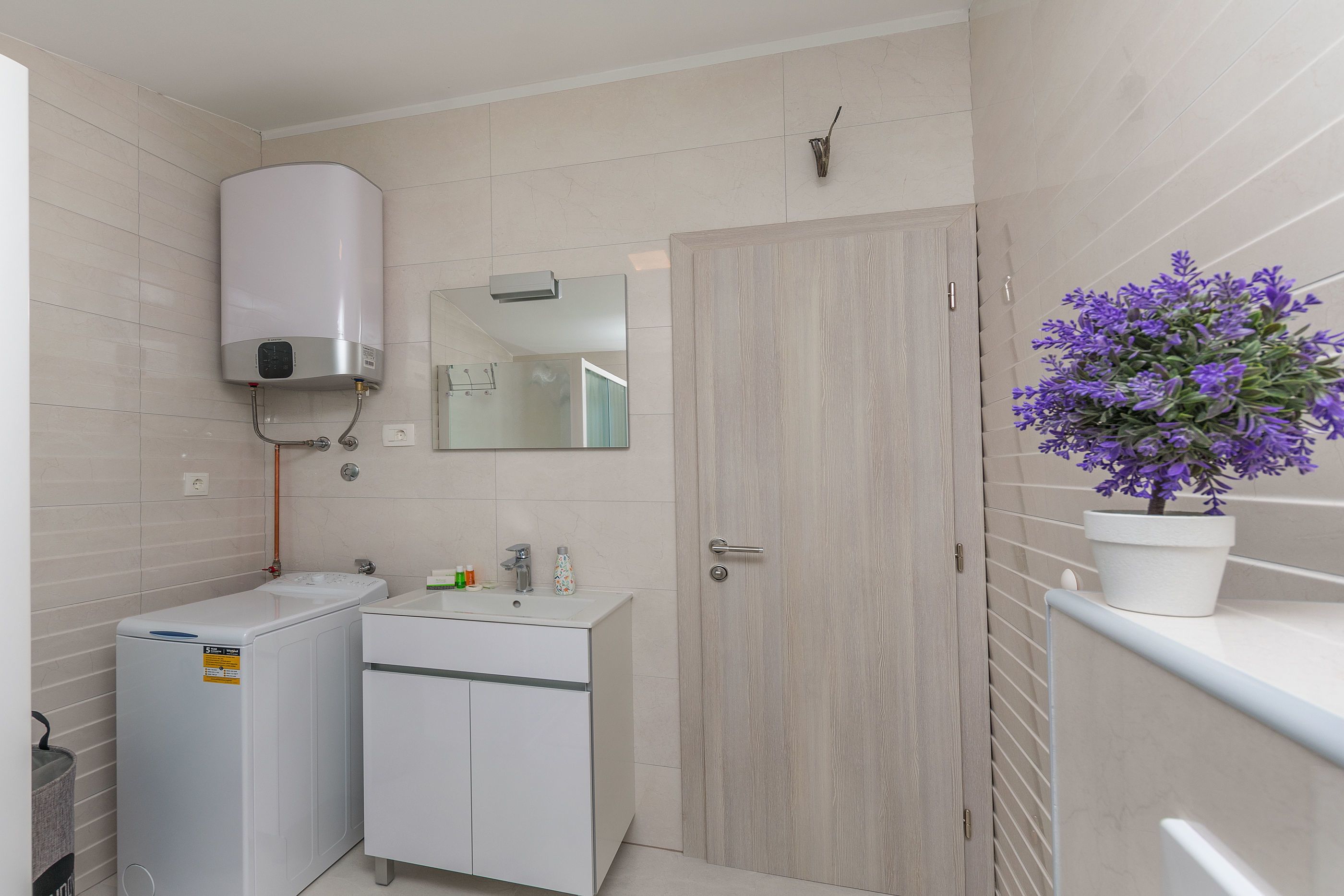 A modern bathroom with a built-in heater, a sink with a mirror, and a potted plant.
