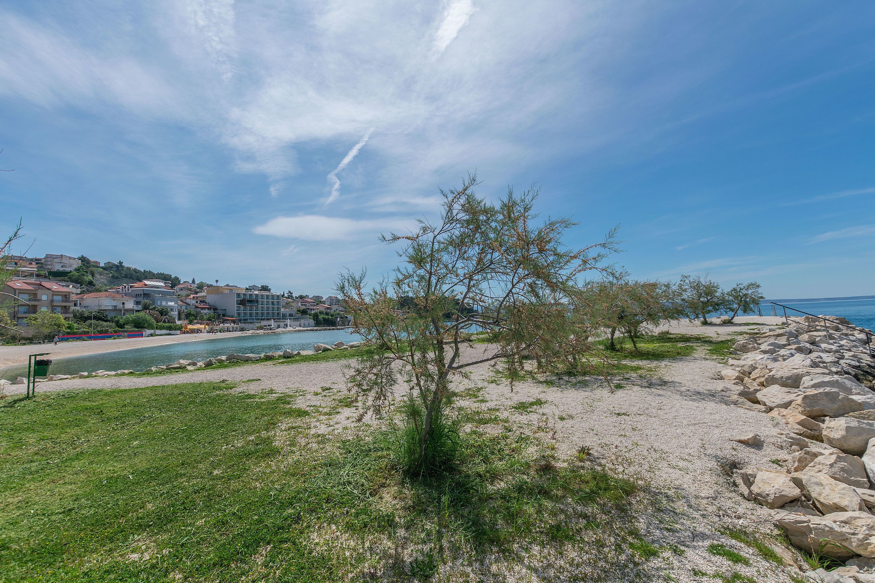 Un paysage côtier avec un ciel dégagé, une côte rocheuse et une vue sur une ville en arrière-plan.