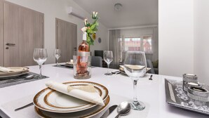A dining table set with plates, glasses, and a centerpiece. - Apartment Heaven (Strozanac)