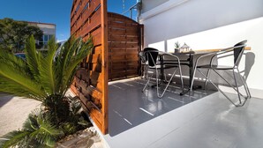 Une terrasse extérieure moderne, agrémentée d’une clôture en bois, d’une table avec des chaises et d’une plante en pot.