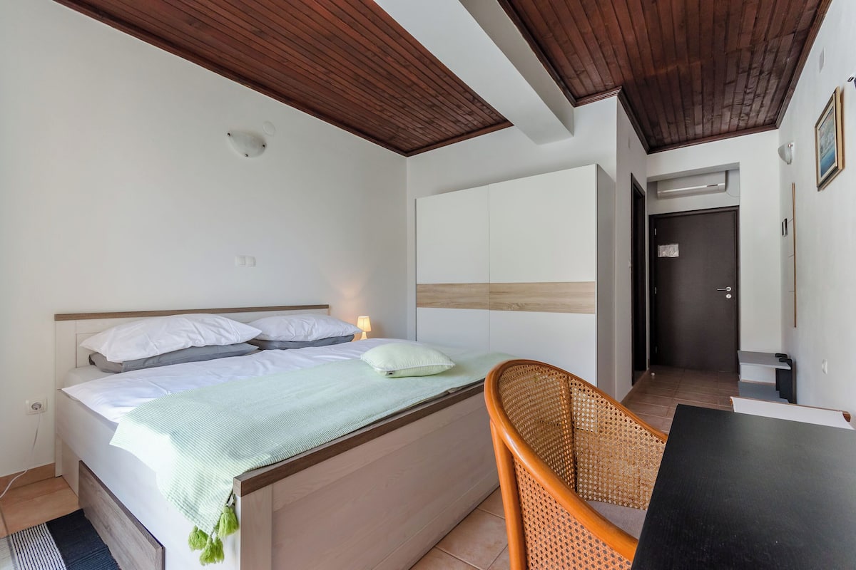 A bedroom with a bed, bedside table, and a chair.