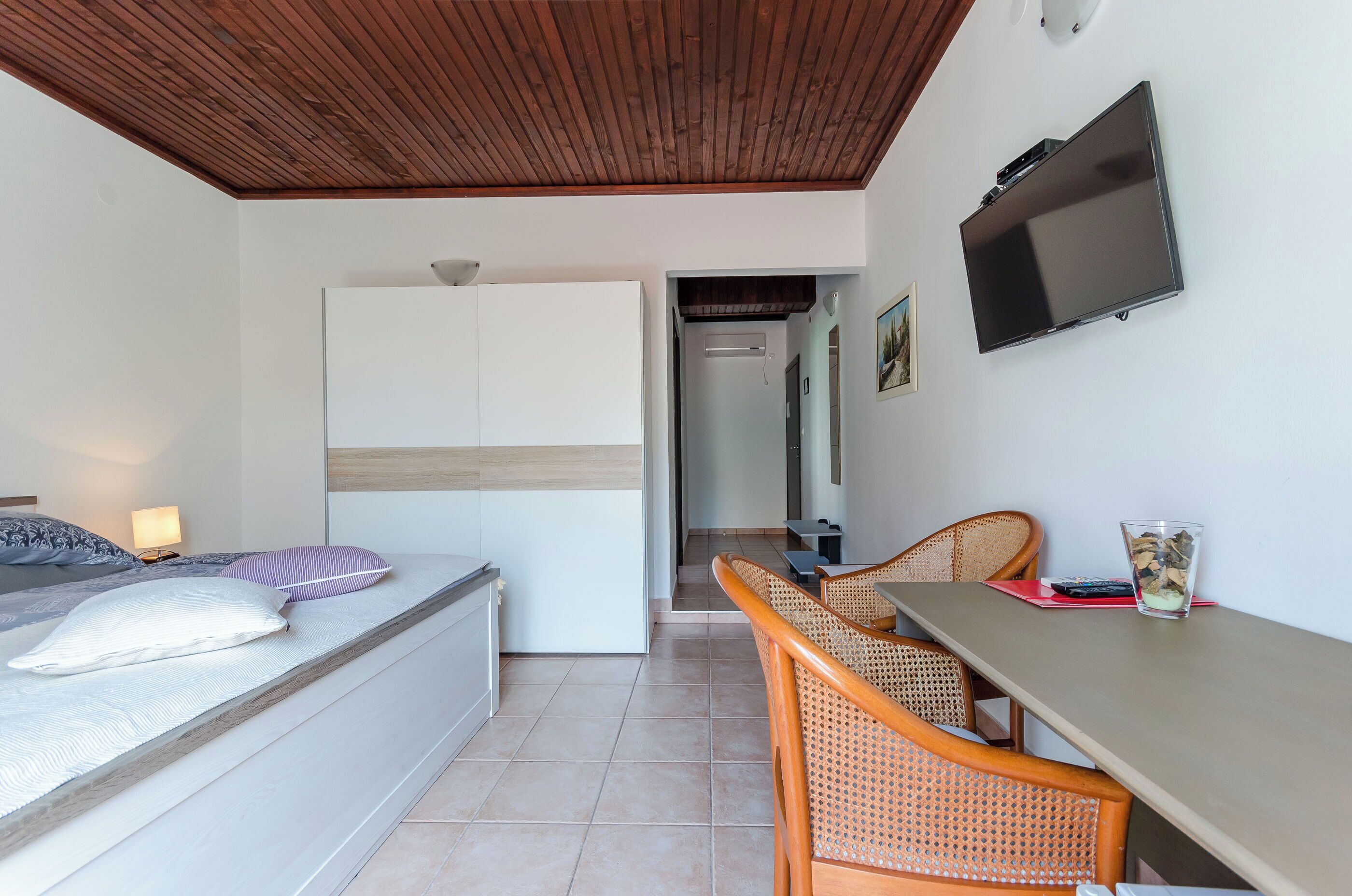 A bedroom with a bed, a desk, and a TV.