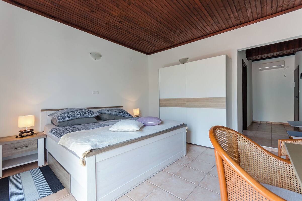 A bedroom with a bed, bedside tables, a lamp, a chair, and a wardrobe.