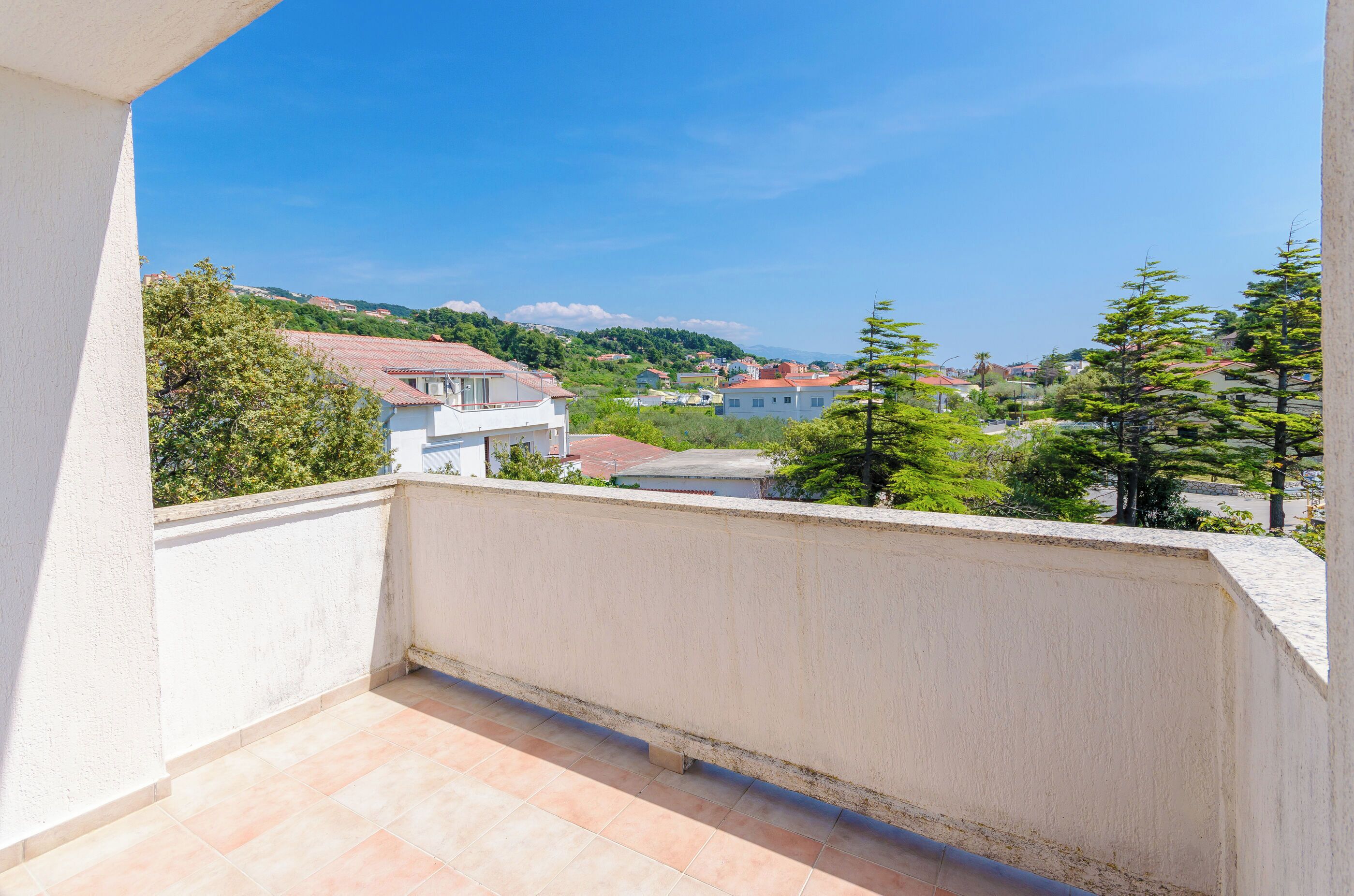 Varanda com vista para uma área residencial, com casas e árvores.