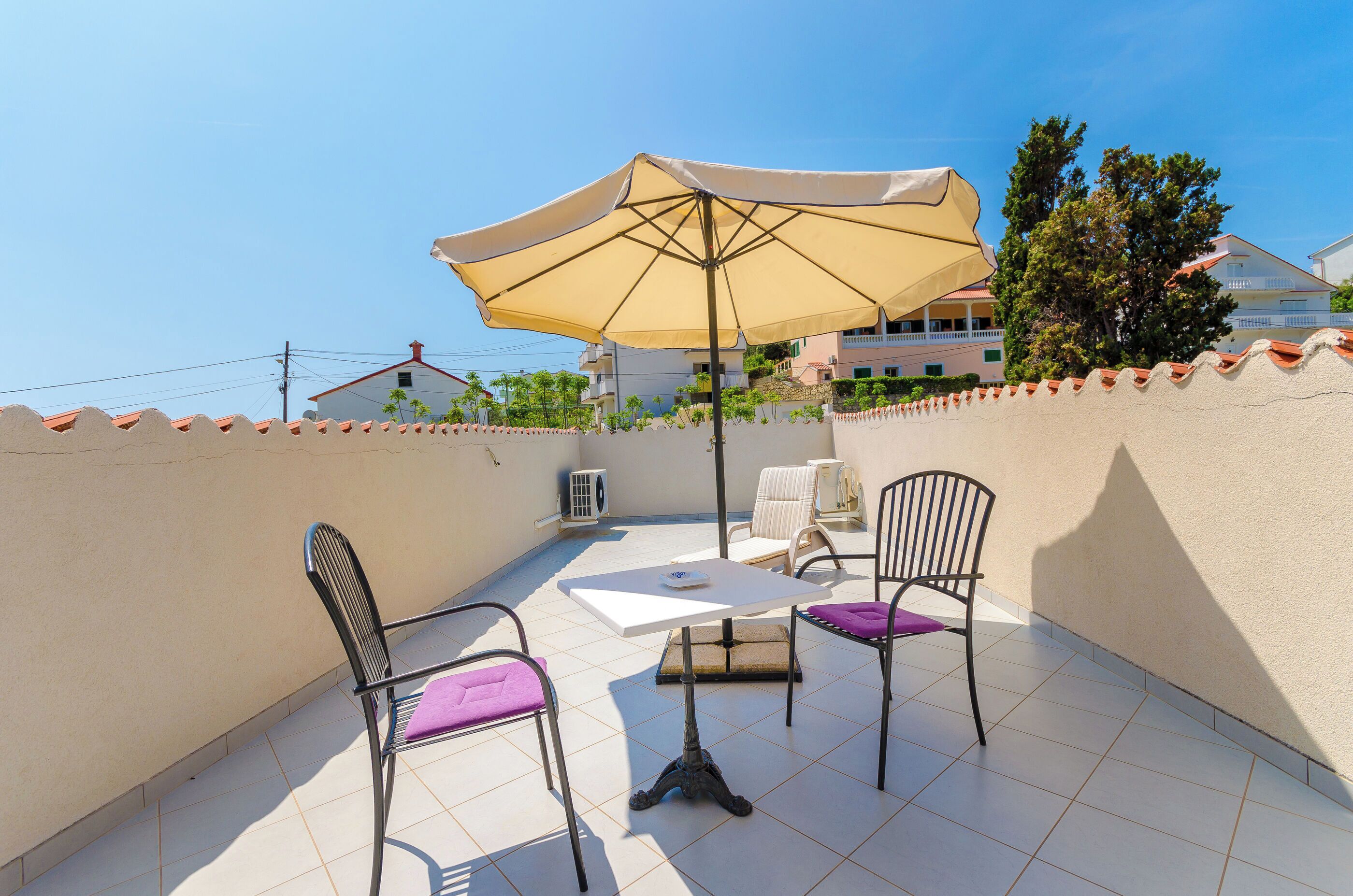 An outdoor patio with a table, chairs, and a large umbrella.