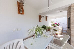 Een kamer met een witte tafel, witte stoelen, een kamerplant en een stenen muur.