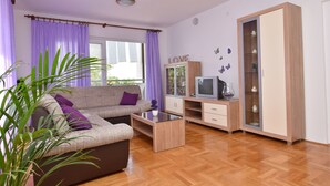 Una sala de estar con sofá, mesa de centro, televisor y aparador.