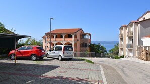 Zona residencial con un coche rojo y una furgoneta blanca estacionados en una calle pavimentada.