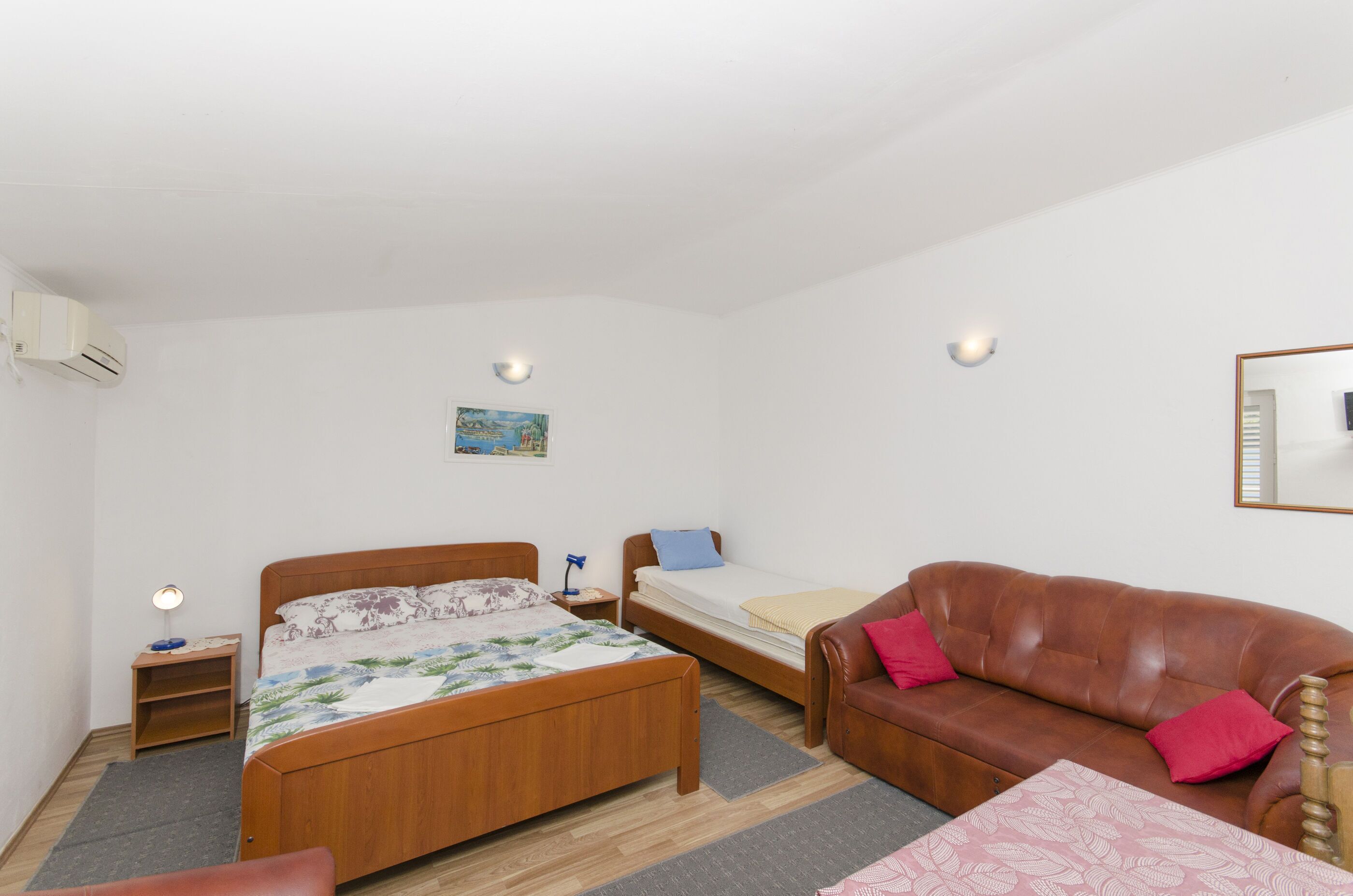 Un dormitorio con cama de madera, un sofá, una mesita y una mesilla de noche.