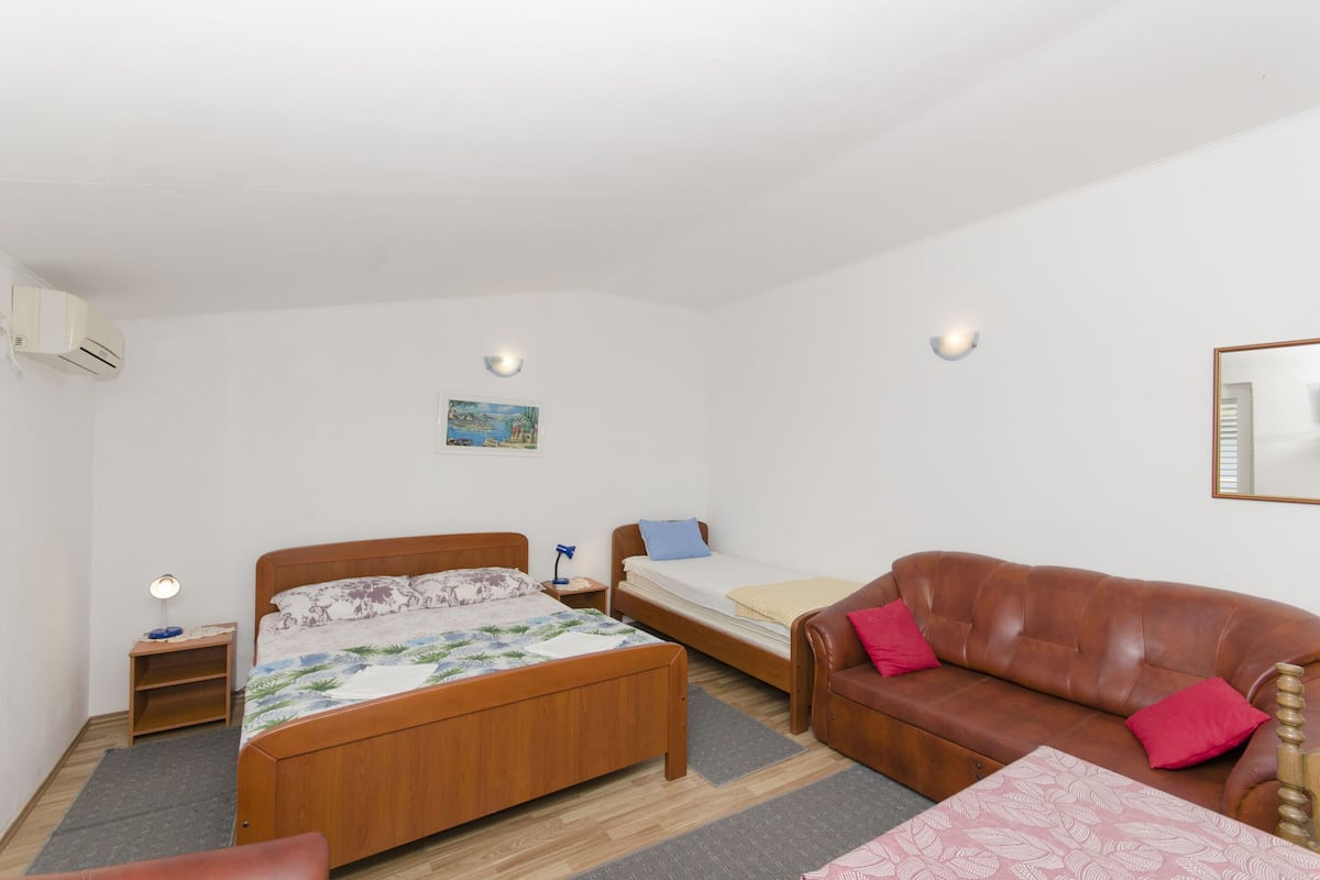 A bedroom with a wooden bed, a sofa, a small table, and a nightstand.