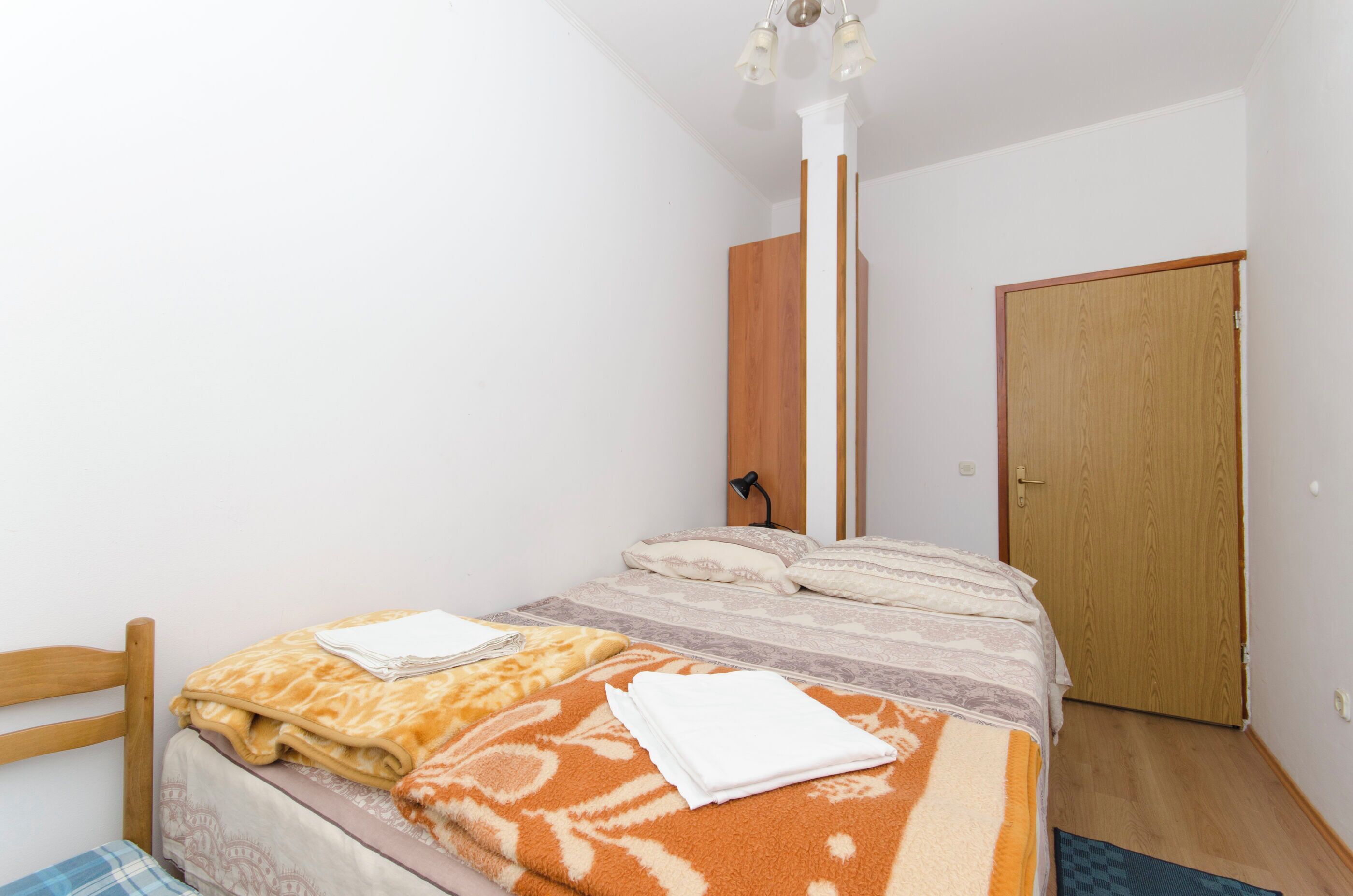 A bedroom with a bed, a wooden headboard, a wooden wardrobe, and a door.