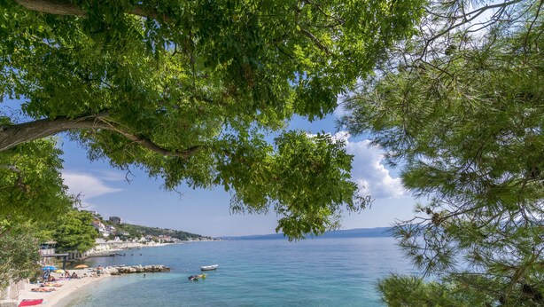 A coastal view with clear waters, a sandy beach, and a small boat. - Apartment Anja (Jesenice)